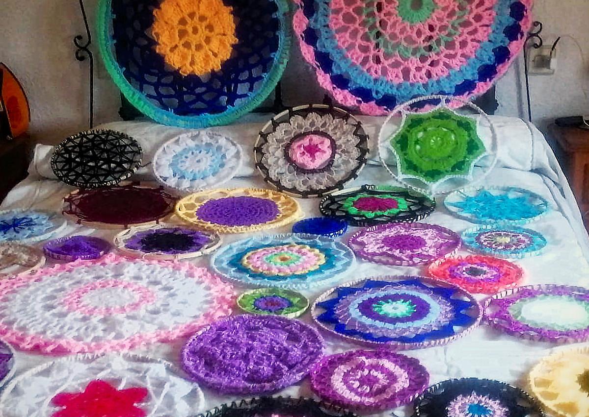 Imagen secundaria 1 - Algunas de las mandalas que ya han elaborado y una de las mujeres tejiendo. 