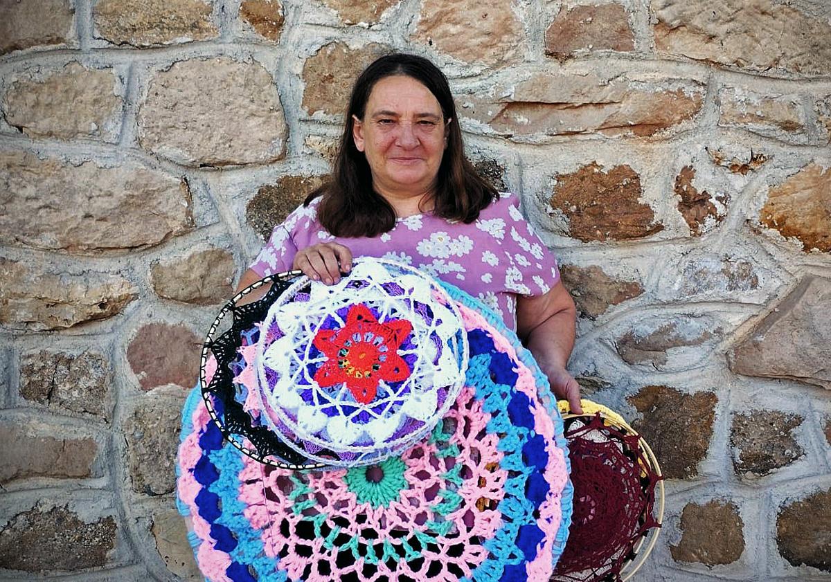 Imagen principal - Algunas de las mandalas que ya han elaborado y una de las mujeres tejiendo. 