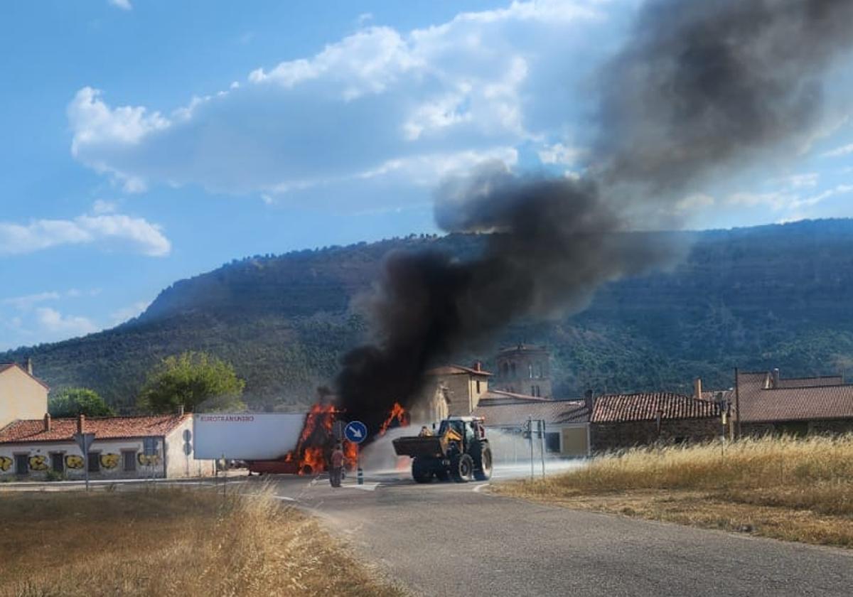 El camión en llamas mientras un hombre intenta sofocar el fuego en Barbadillo del Mercado.