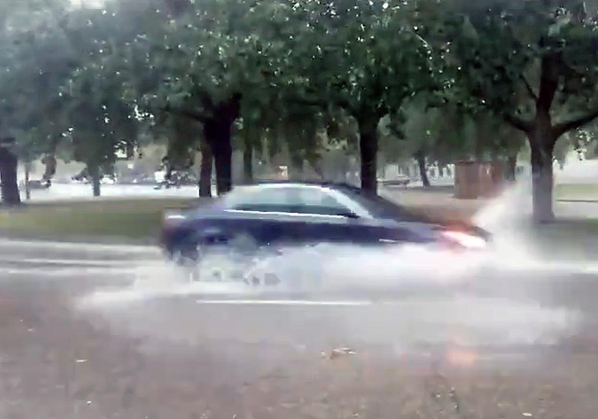 Un coche circula por una calle de Burgos annegada de agua.