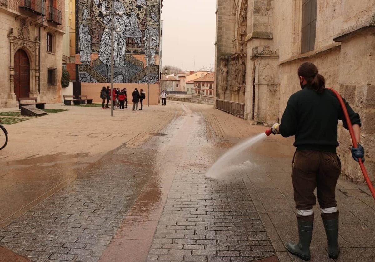 Una operaria limpia la calle en un episodio de calima en Burgos.