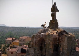 La cigüeña en uno de sus nidos con el pueblo de Hacinas al fondo.