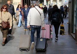 Unos turistas tiran de sus maletas.