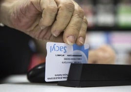 Un farmacéutico pasa una tarjeta sanitaria.