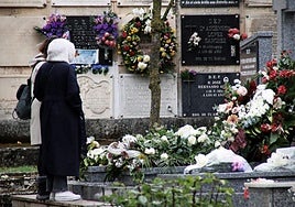 Dos personas observan una tumba del cementerio de Burgos