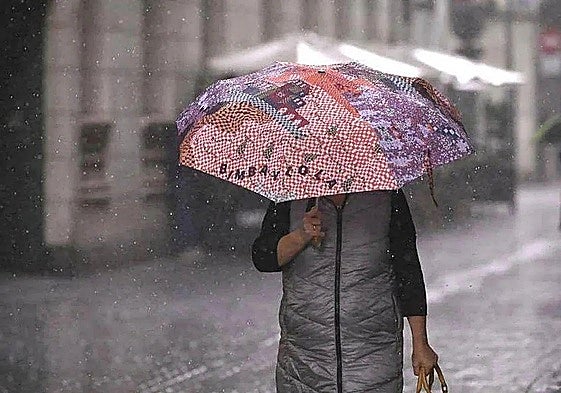 Una mujer se cubre como puede de la lluvia.