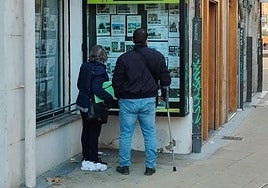 Una pareja observa los anuncios en una inmobiliaria.