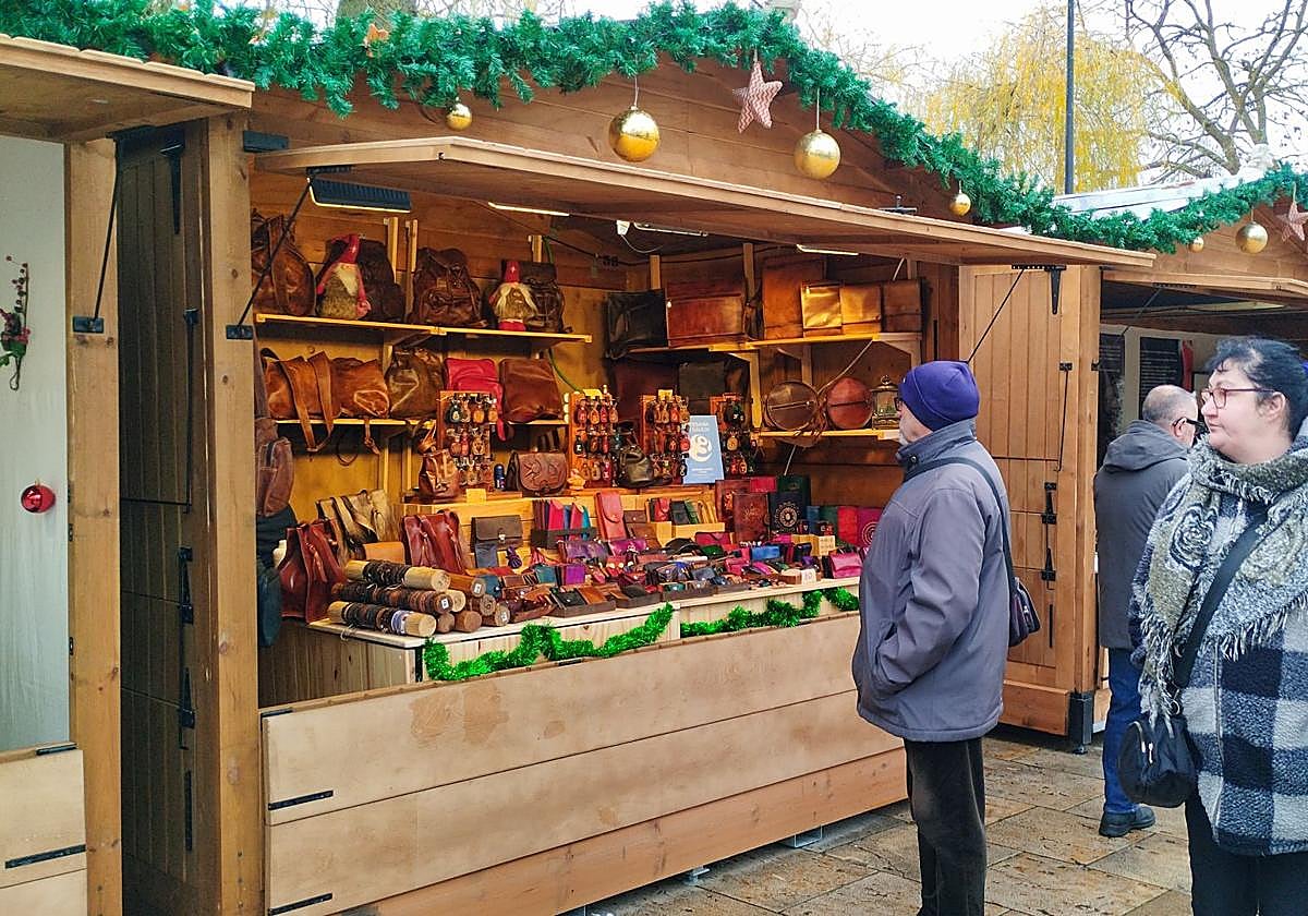 Dos personas observan un puesto del mercado navideño en el paseo del Espolón.