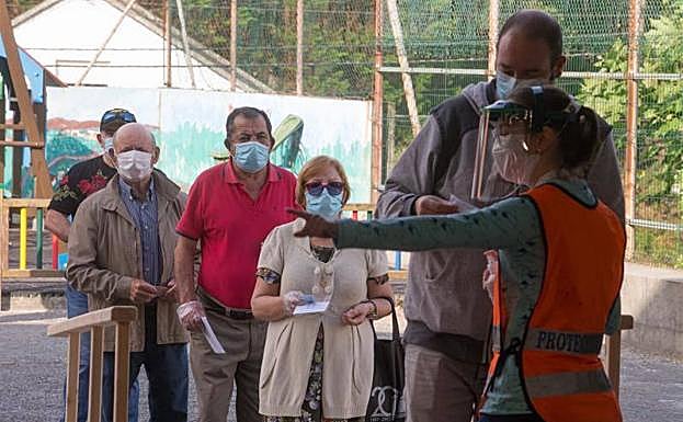 Vecinos de Burela (Lugo) hacen cola este domingo frente a un colegio electoral.