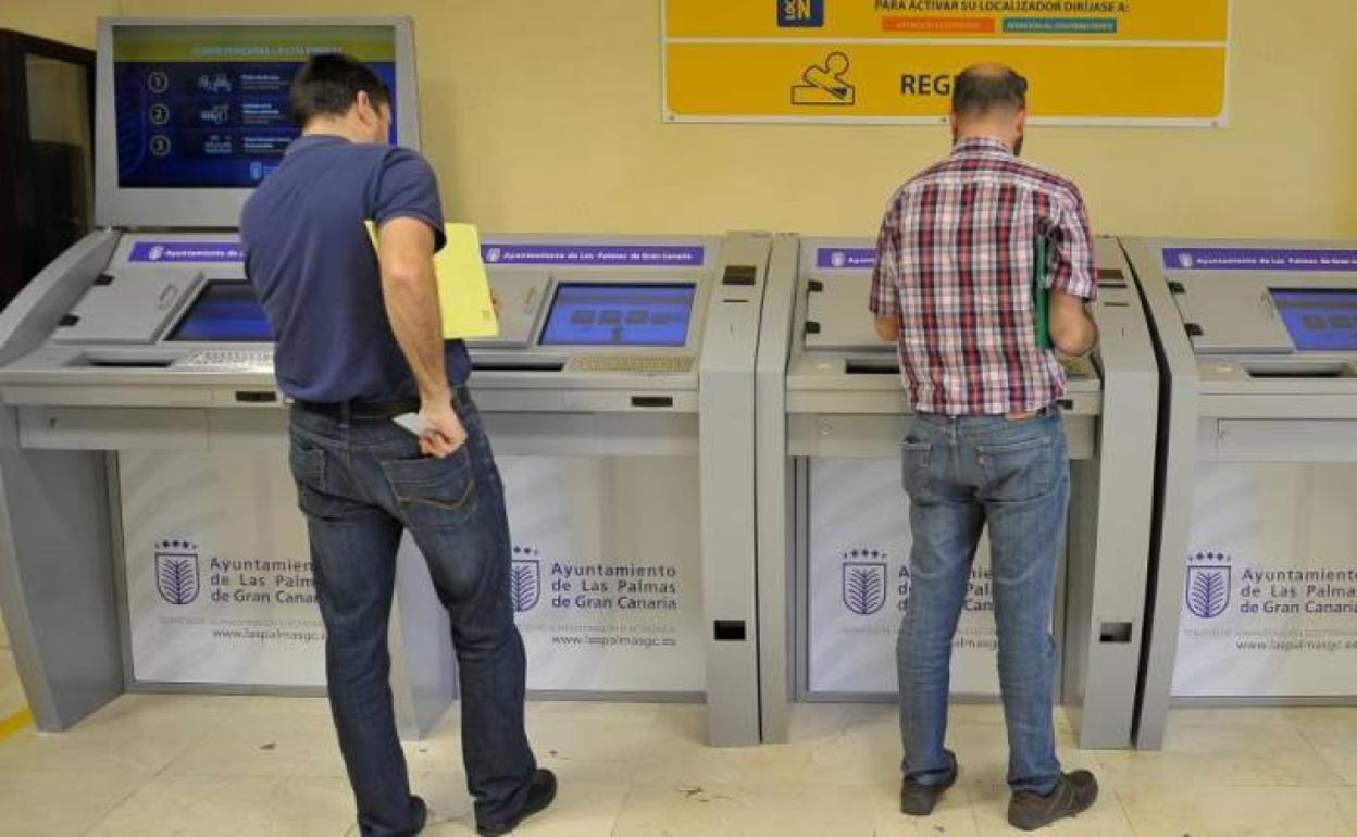 Dos personas pagando impuestos en el Ayuntamiento de Las Palmas de Gran Canaria. 