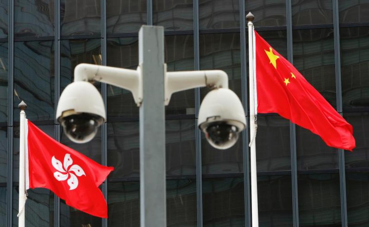 Banderas nacionales de Hong Kong y China detrás de un par de cámaras de vigilancia
