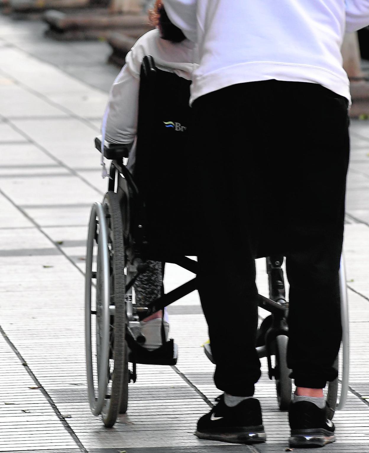 Foto de archivo de una persona dependiente paseando con su cuidadora. 
