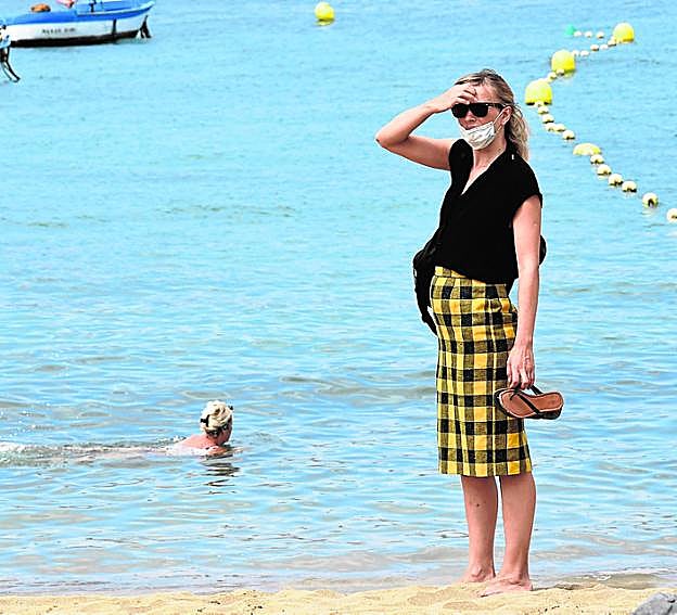 Personas con mascarilla en Las Canteras. 