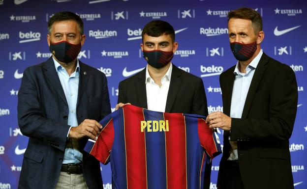 El centrocampista canario, Pedro González «Pedri» (c) acompañado por el presidente del FC Barcelona, Josep Maria Bartomeu (i) y del responsable de la secretaría técnica, Ramon Planes