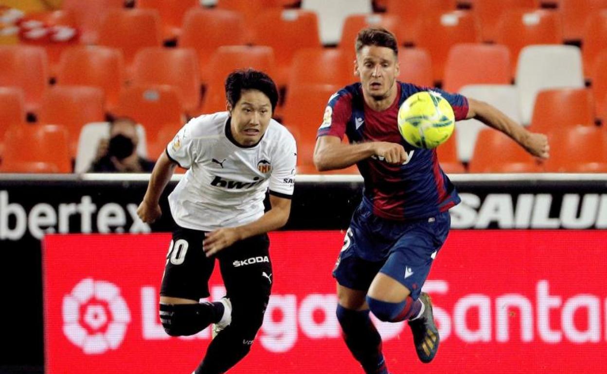 El surcoreano Kang-In Lee, del Valencia, pugna por un balón con Nemanja Radoja, del Levante. 