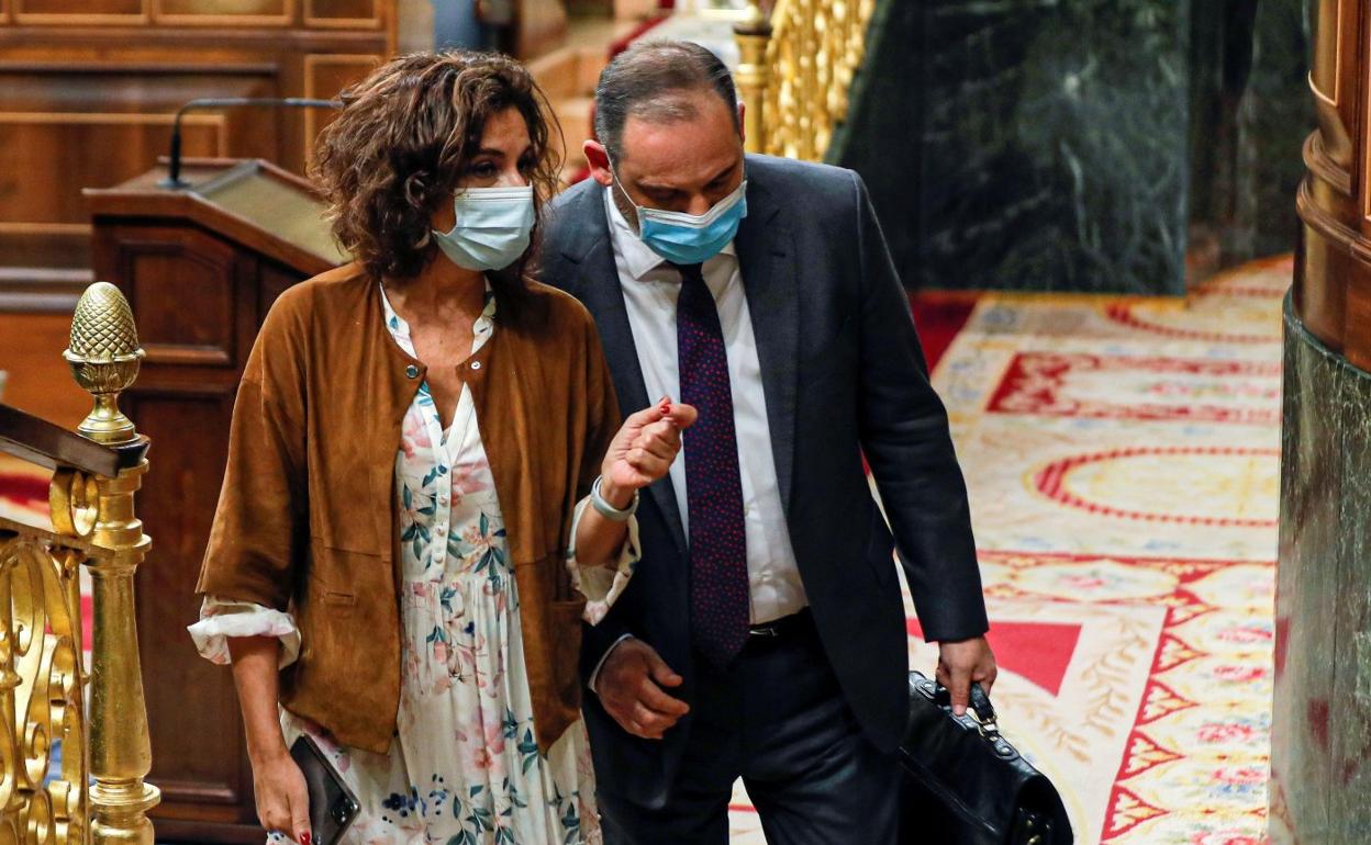 La ministra de Hacienda, María Jesús Montero, habla con un diputado durante el pleno del Congreso. 