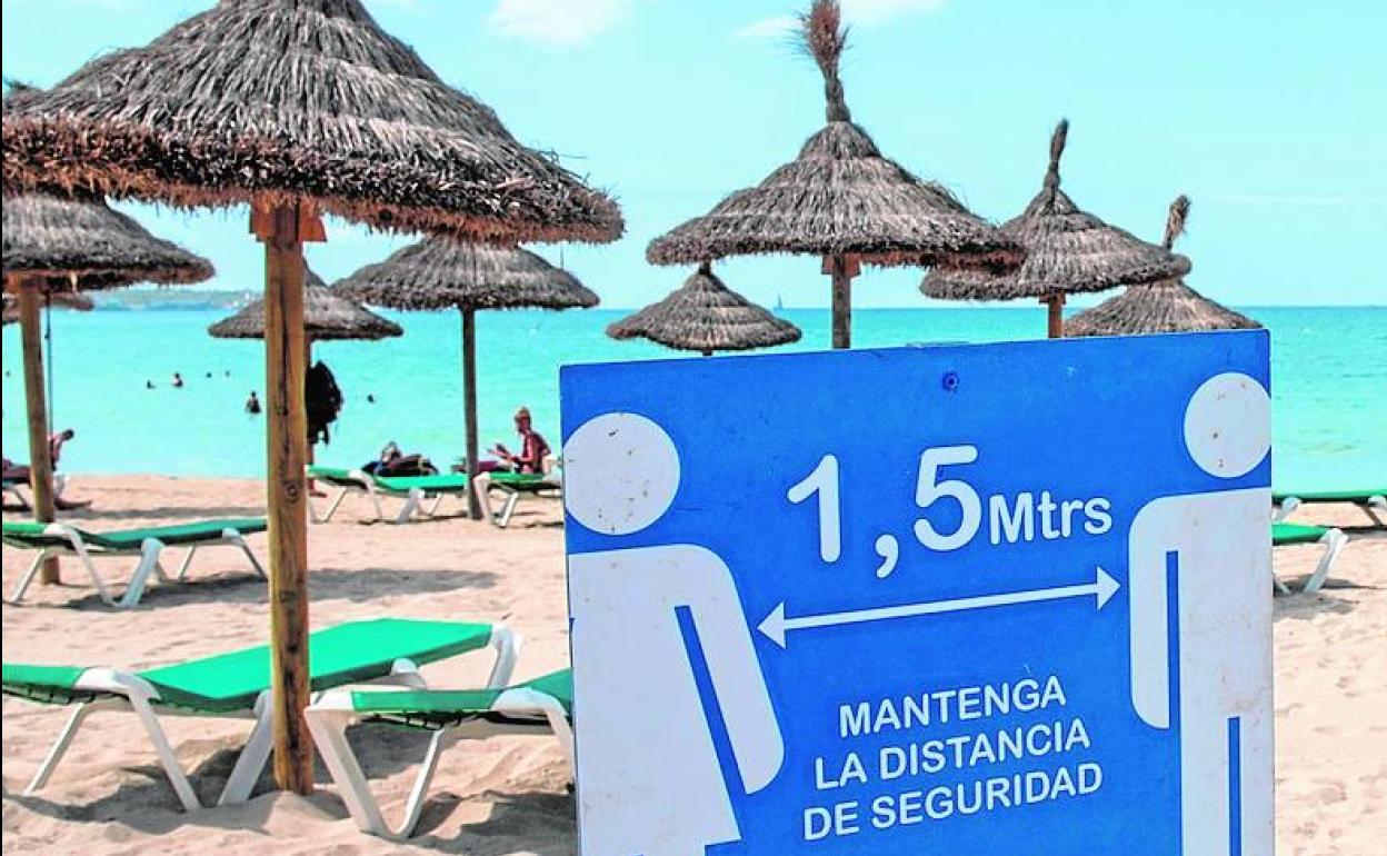 Un cartel recuerda la distancia social en la playa. 