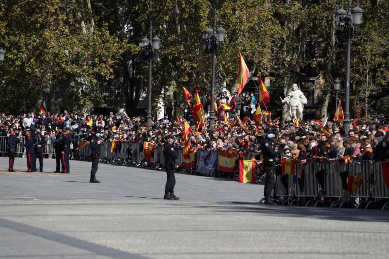 Un grupo de personas asisten al desfile durante el acto organizado con motivo del Día de la Fiesta Nacional, en Madrid