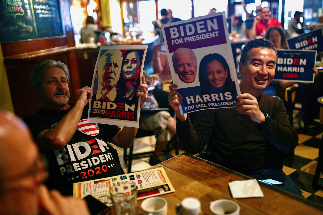 La gente sostiene carteles y letreros de apoyo a Biden y Harris mientras ven los resultados en vivo. 