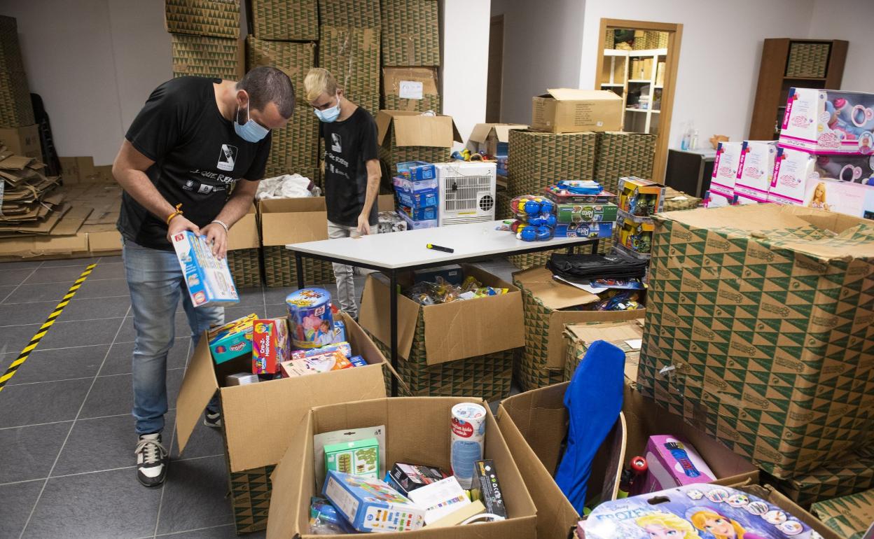 Dos voluntarios de la Casa de Galicia organizan los primeros juguetes comprados con la donación de 6.000 euros del Ayuntamiento. 