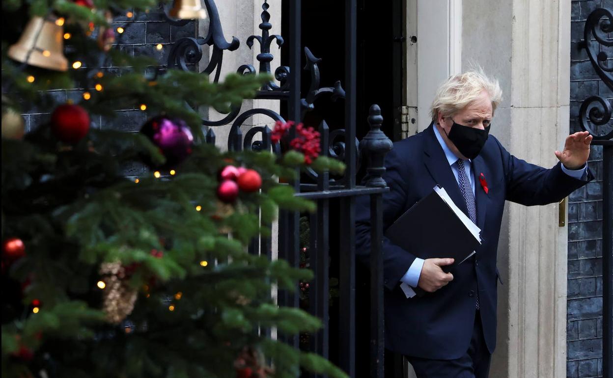 El primer ministro, Boris Johnson, saluda al salir de Downing Street camino del Parlamento para defender su plan navideño contra la covid.