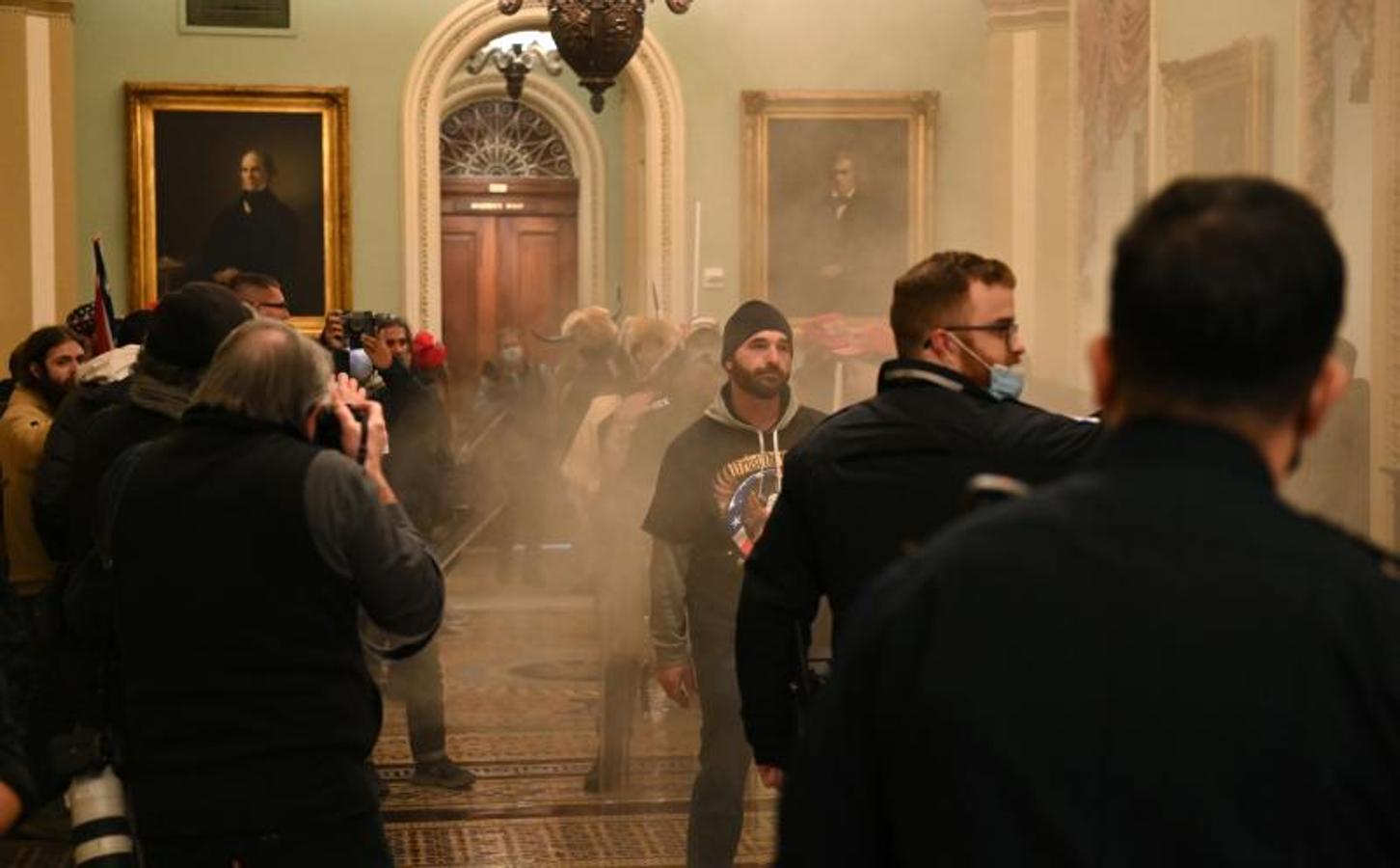 Los partidarios del presidente de los Estados Unidos, Donald Trump, ingresan al Capitolio de los Estados Unidos mientras el humo llena el corredor.