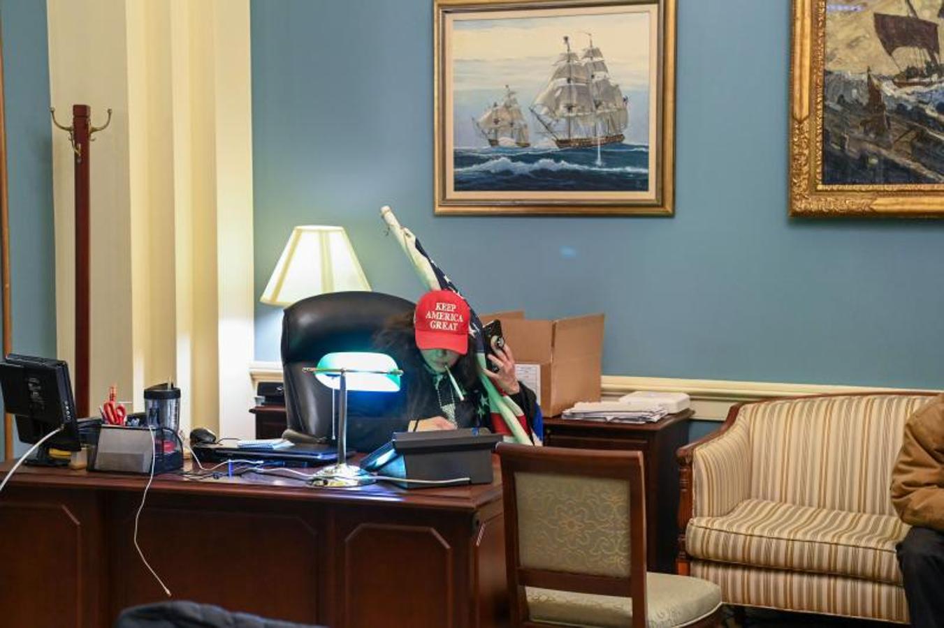 Un partidario del presidente de los Estados Unidos, Donald Trump, se sienta en un escritorio después de invadir el edificio del Capitolio