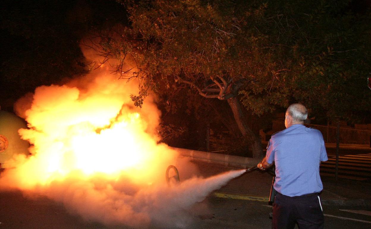 Un policía extingue el incendio de un contenedor. 