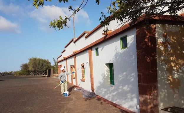 Un alumno pinta el exterior del albergue. 