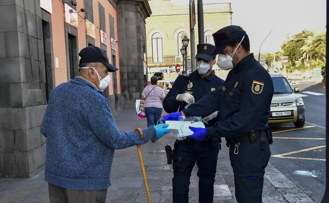Agentes policiales entegando mascarillas junto al Mercado de Vegueta.