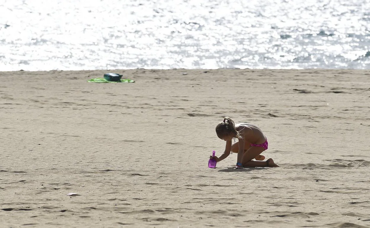 Una niña juega en la arena, en la playa de Maspalomas. 