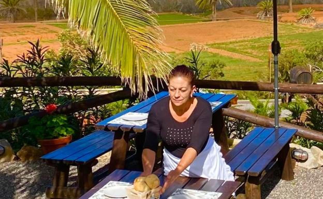 Auxi Méndez atiende en las mesas del café bar & tapas, con las gavias cultivadas al fondo. 