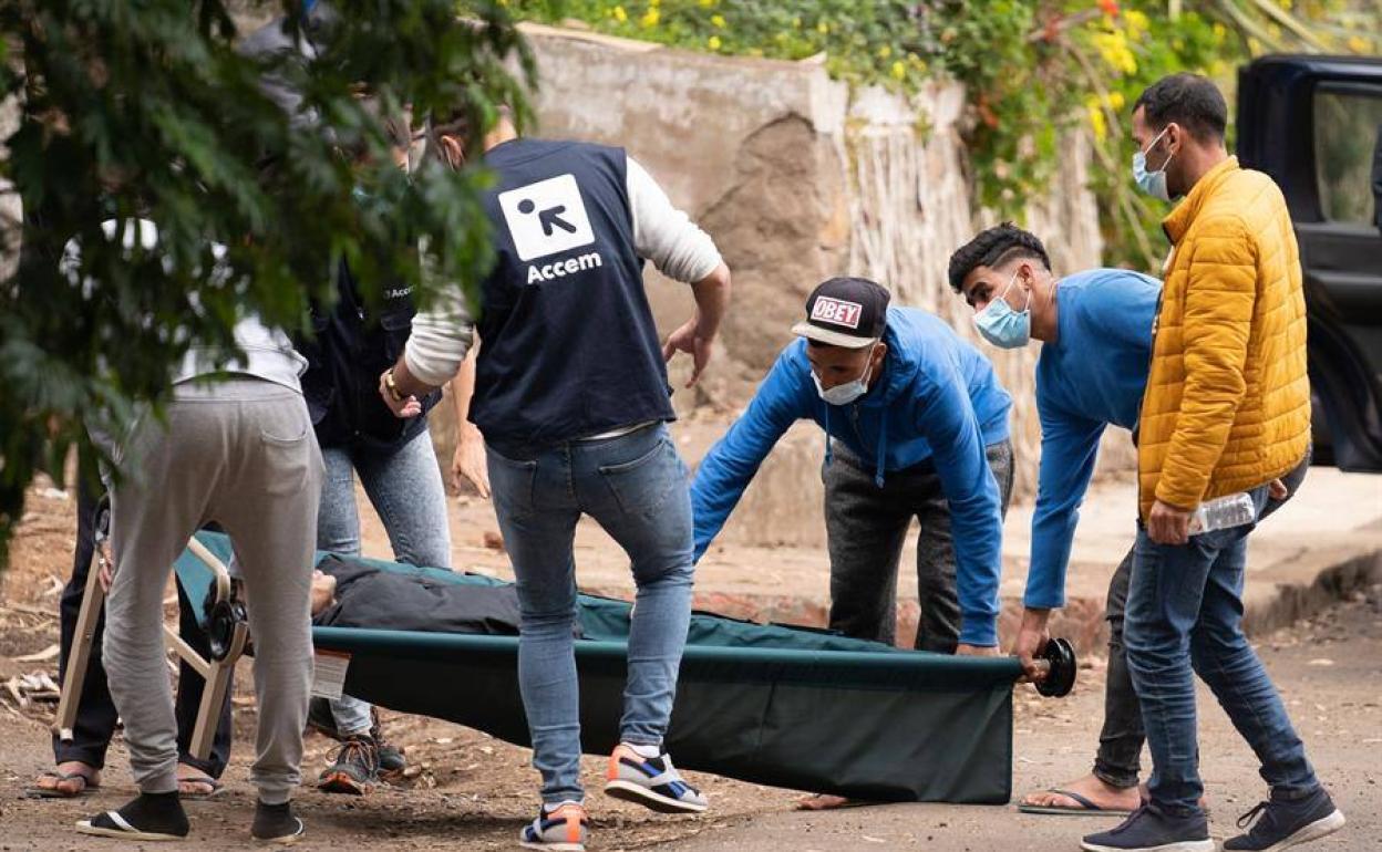 En la imagen, unos inmigrantes y personal de la ONG Accem, que gestiona el campamento, trasladan a uno de los heridos en los altercados