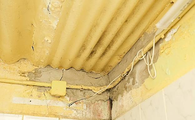 Techo del baño, con plancha de amianto y presencia de humedades en las paredes. 