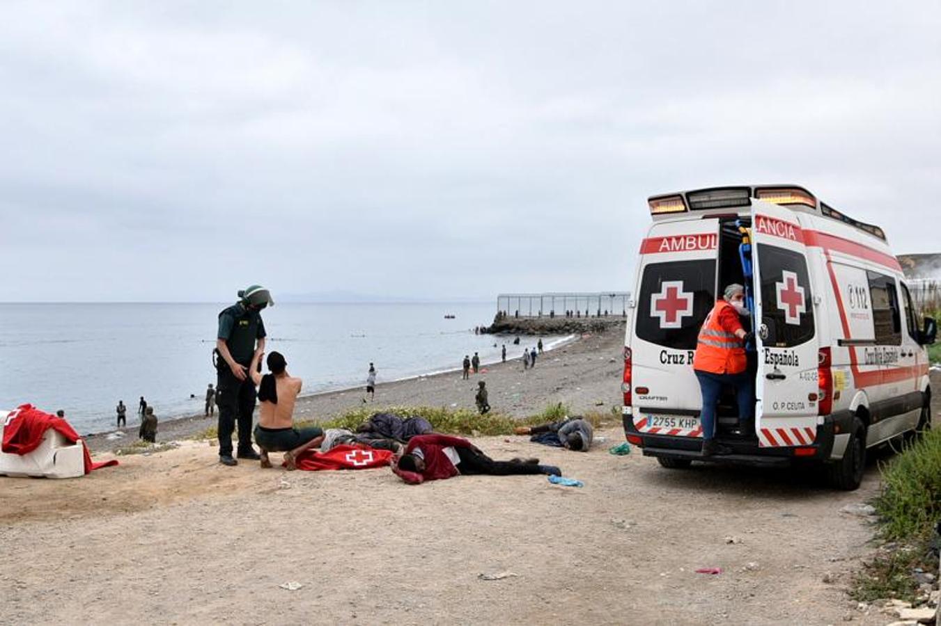 Un migrante que llegó nadando al enclave de Ceuta habla con una Guardia Civil.