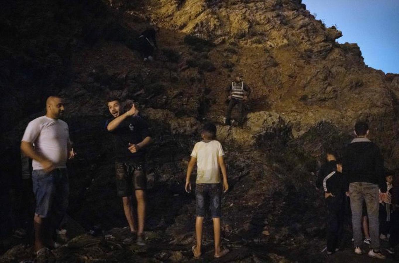 Los migrantes marroquíes escalan un acantilado rocoso en la ciudad norteña de Fnideq mientras intentan cruzar la frontera de Marruecos al enclave español de Ceuta.