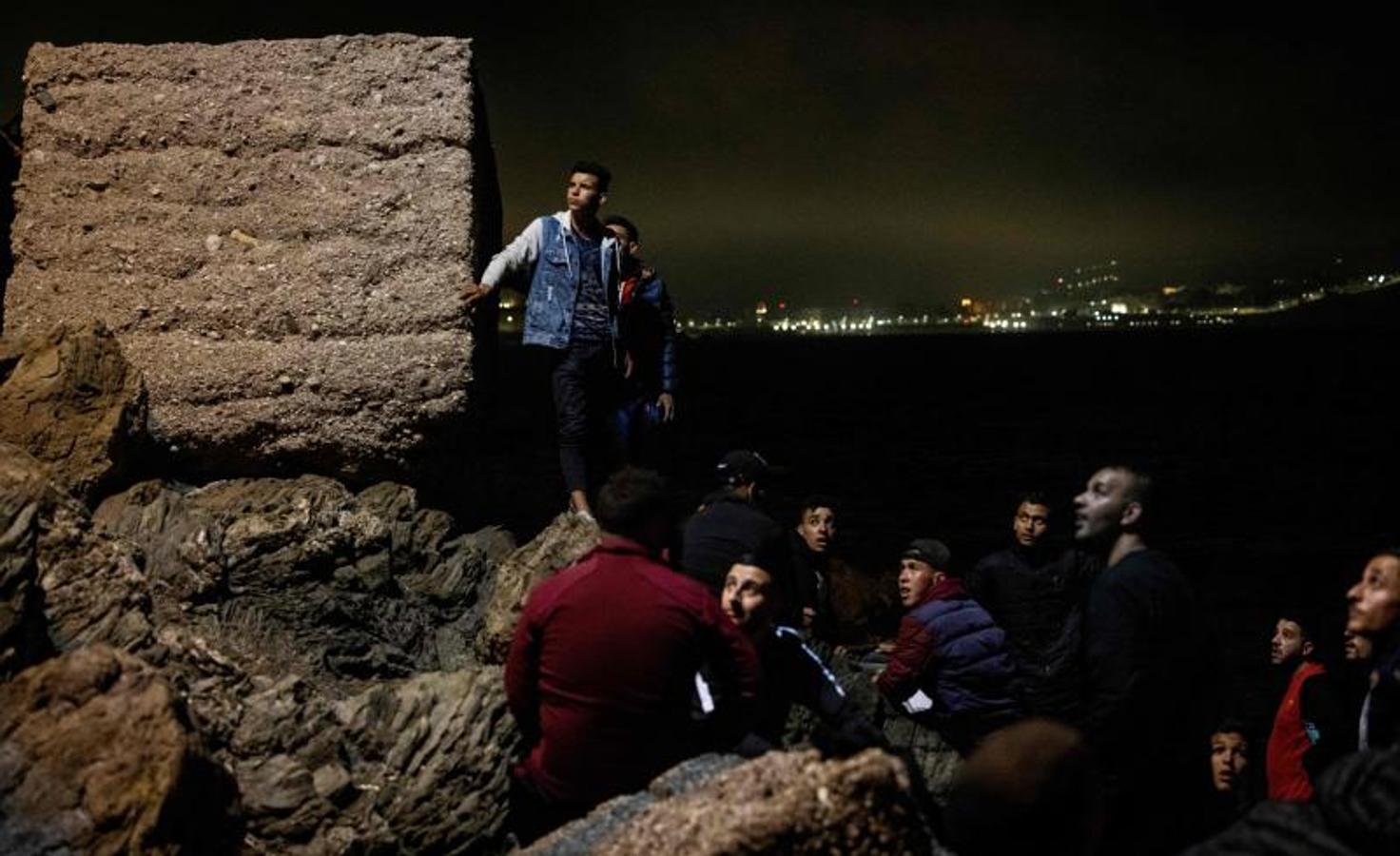 Migrantes marroquíes trepan por un acantilado en la ciudad norteña de Fnideq mientras intentan cruzar la frontera de Marruecos al enclave español de Ceuta.