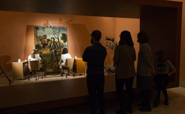 Un grupo de visitantes observa la restauración del cuadro, que se hizo de cara al público. 