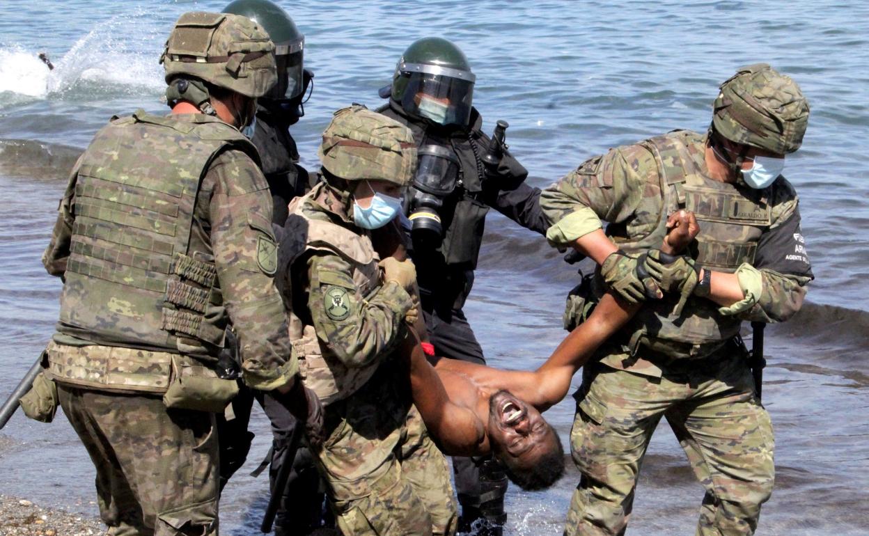 Imagen del pasado martes de varios militares ayudando a un inmigrante que llegó a la costa de Ceuta. 