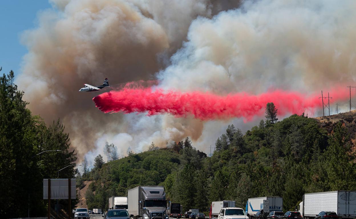 Un avión trata de sofocar un incendio junto a una transitada autopista en California, cerca de la ciudad de Shasta Lake.