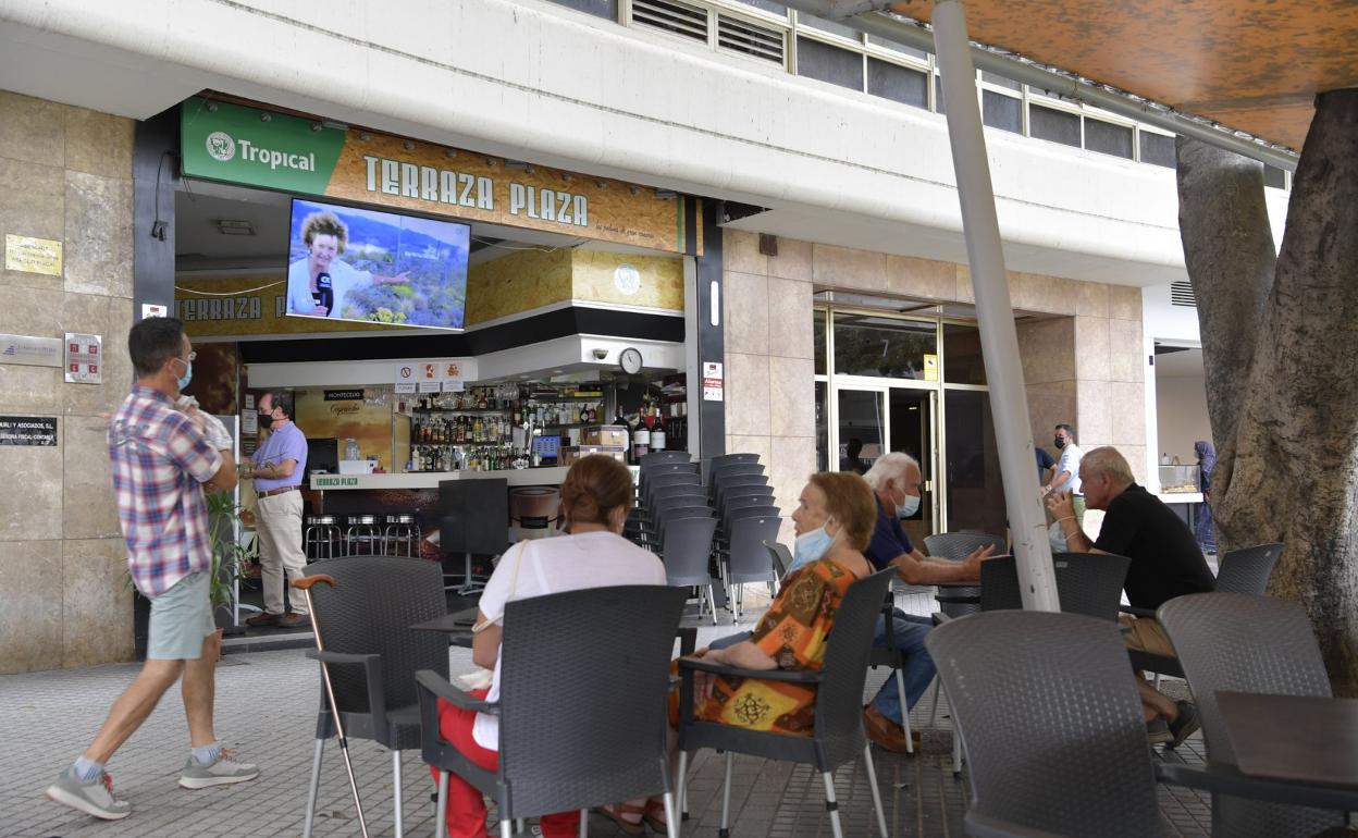 Varias personas siguiendo la información sobre el volcán de La Palma en una terraza. 