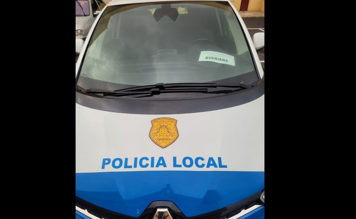 Detalle de un coche patrulla con el cartel de averiado. 