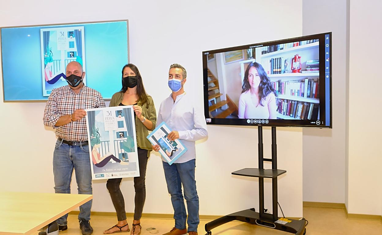 El presidente Sergio Lloret, la diseñadora Yaiza Castilla y el consejero de Cultura, Rayco León. En la pantalla, María Oruña. 