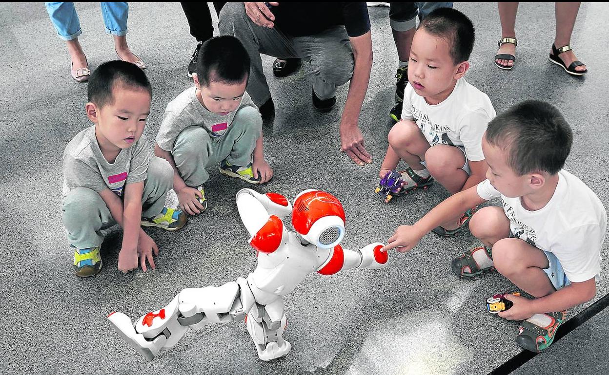 Un grupo de niños chinos juegan con un robot que hace taichí en Pekín