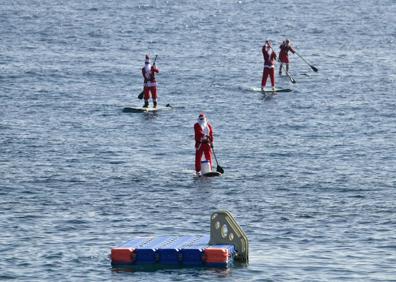 Imagen secundaria 1 - Papá Noel llega a Arinaga haciendo paddle surf
