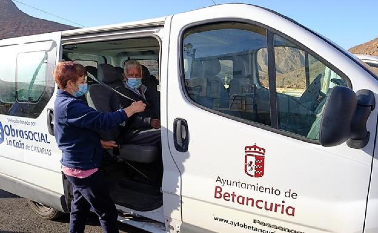 Reyes ayuda a poner el cinturón a Antoñito, de 98 años, el usuario más mayor dle programa municipal de Ayuda a Domicilio., para trasladarlo hasta el supermercado de Antigua. 