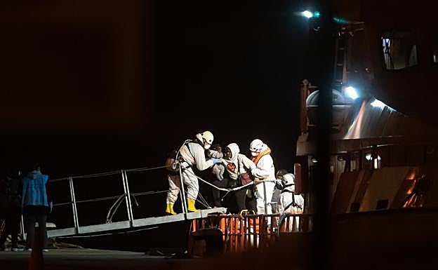 Miembros del operativo de emergencia ayudan a desembarcar a una mujer y su bebé tras recatarlos en Fuerteventura. 