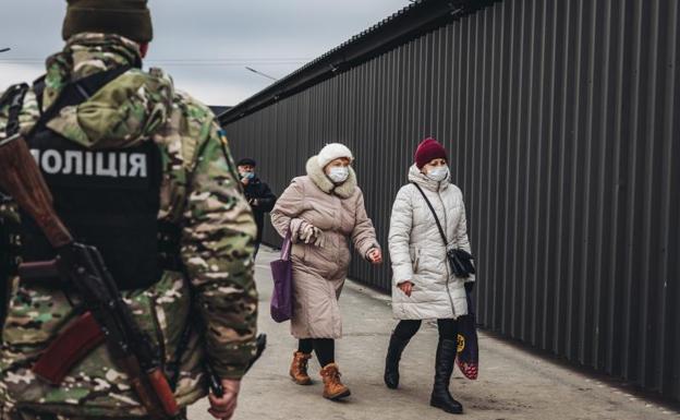 Dos mujeres caminan delante de un policía en el control fronterizo de Stanitsa Luganska para cruzar del territorio ucraniano al territorio de la autoproclamada República de Lugansk. 