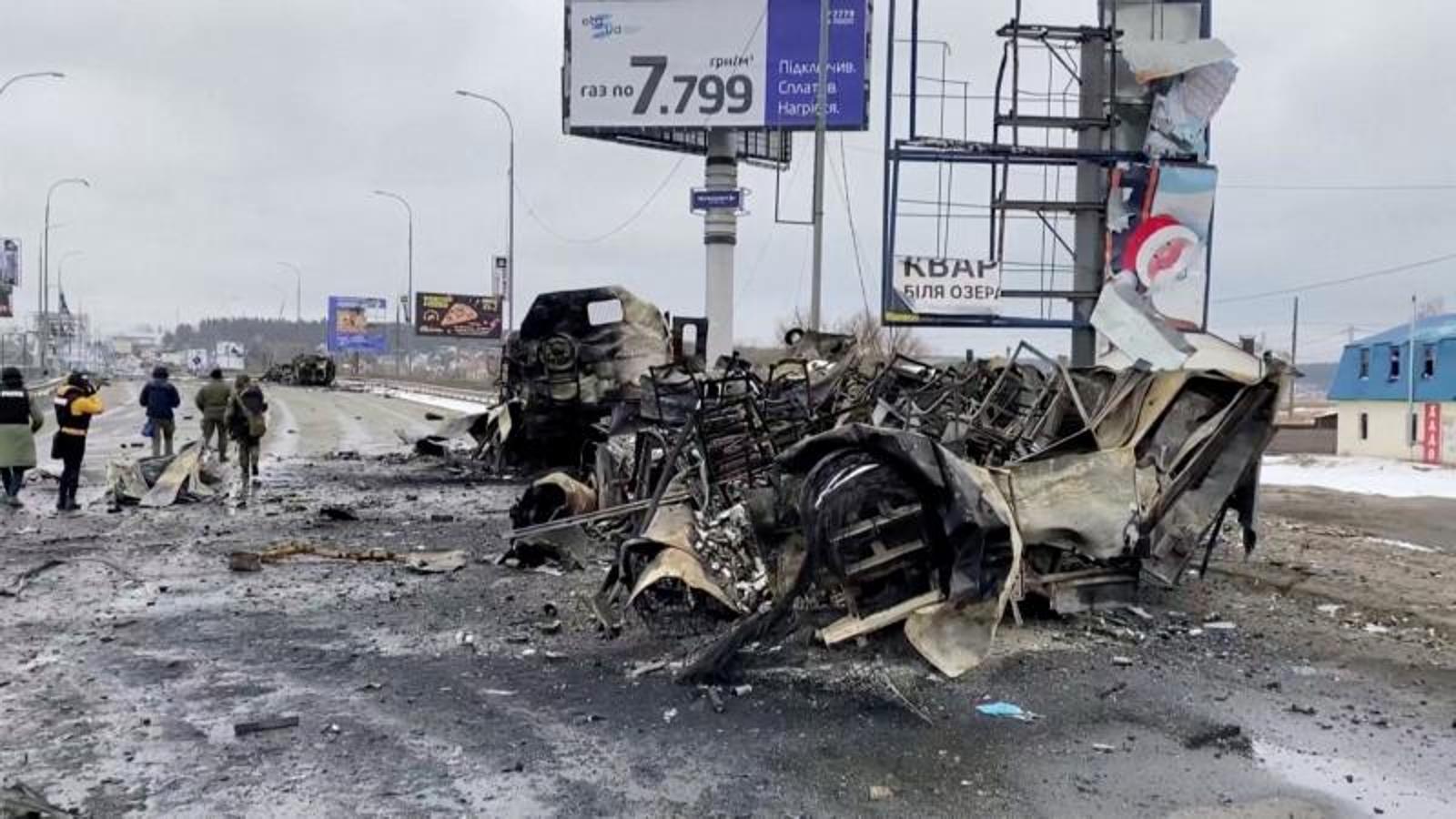 Un grupo de periodistas pasa junto a un vehículo en Bucha, ciudad cercana a Kiev. 