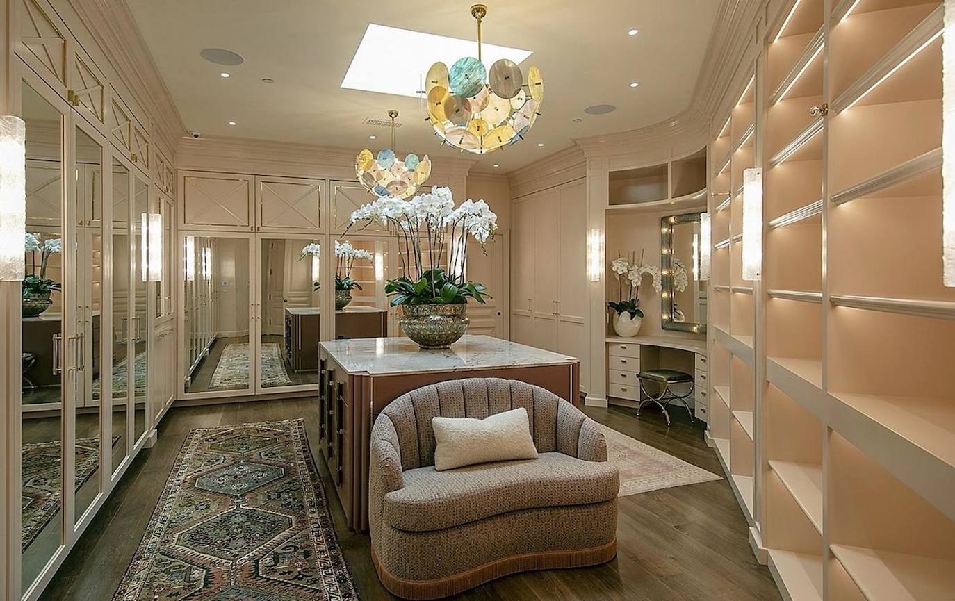 La suite principal posee este gran vestidor en el que hay tanto armarios como estanterías, una gran isla central y tocador.